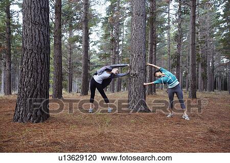 Stock Image - Runners stretching in forest. Fotosearch