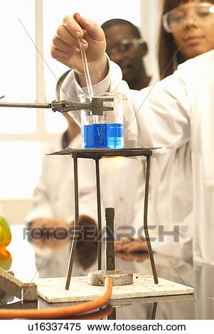 Stock Photography - Scientist adding solution to beaker. Fotosearch