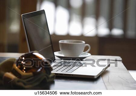 Stock Photograph - Ski goggles and laptop with coffee cup. Fotosearch