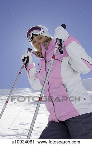 Stock Image - Skier holding poles on mountainside. Fotosearch