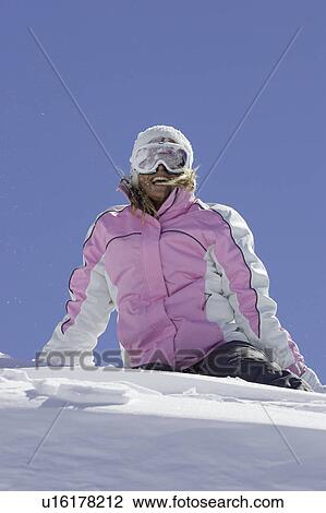 Stock Image - Skier sitting on mountainside. Fotosearch
