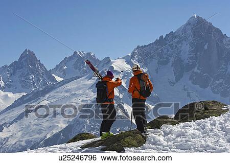 Stock Photograph - Skiers admiring snowy mountain view. Fotosearch