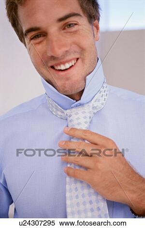 Smiling businessman adjusting his tie View Large Photo Image Stock Photography - Smiling businessman adjusting his tie. Fotosearch