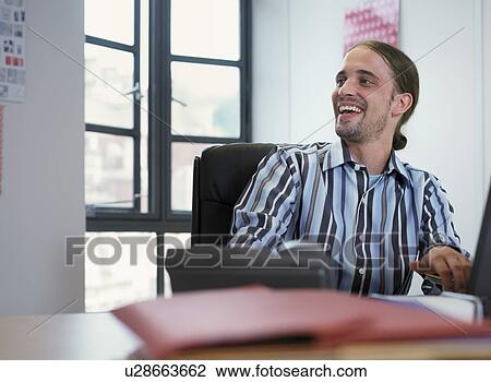 Smiling businessman at desk in office View Large Photo Image Stock Image - Smiling businessman at desk in office. Fotosearch