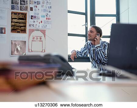Stock Photograph - Smiling businessman on phone in office. Fotosearch