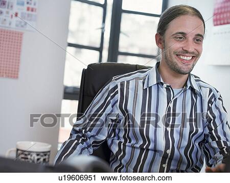 Smiling businessman working at desk View Large Photo Image Stock Image - Smiling businessman working at desk. Fotosearch