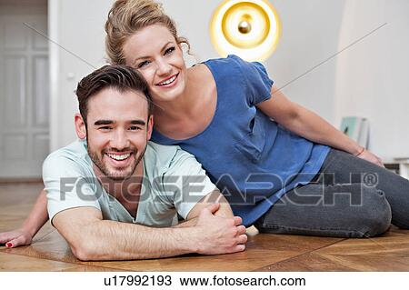 Smiling couple embracing on floor View Large Photo Image Stock Image - Smiling couple embracing on floor. Fotosearch