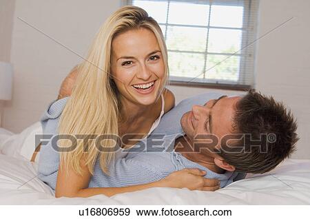 Smiling couple hugging in bed View Large Photo Image Stock Photo - Smiling couple hugging in bed. Fotosearch