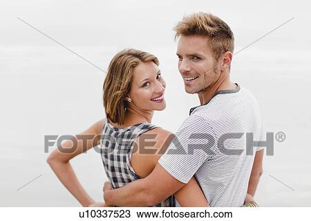 Stock Image - Smiling couple hugging on beach. Fotosearch
