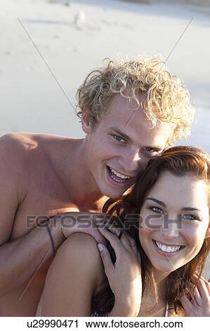 Stock Image - Smiling couple hugging on beach. Fotosearch