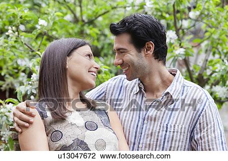 Stock Image - Smiling couple hugging outdoors. Fotosearch