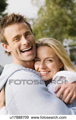 Stock Photo - Smiling couple hugging outdoors. Fotosearch