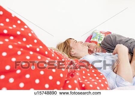 Smiling couple laying in bed together View Large Photo Image Stock Image - Smiling couple laying in bed together. Fotosearch