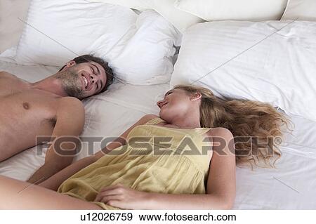 Stock Photo - Smiling couple laying in bed together. Fotosearch