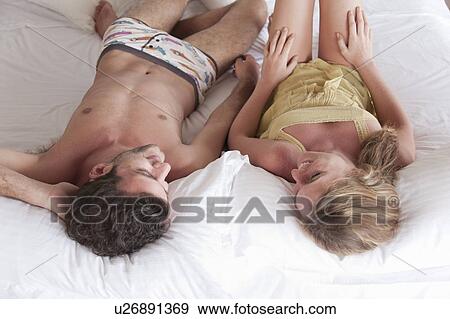 Smiling couple laying in bed together View Large Photo Image Stock Photo - Smiling couple laying in bed together. Fotosearch