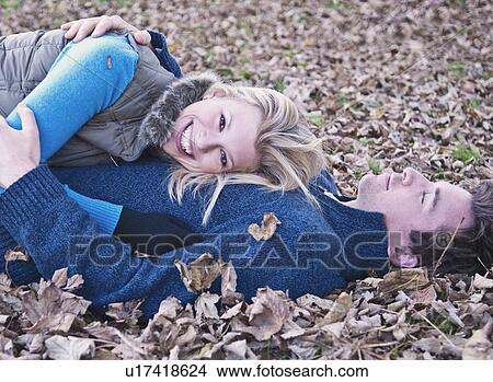 Smiling couple laying in fall leaves View Large Photo Image Picture - Smiling couple laying in fall leaves. Fotosearch