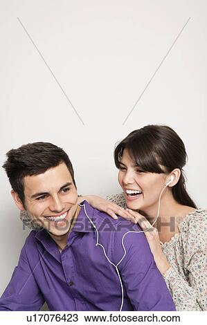 Stock Image - Smiling couple listening to headphones. Fotosearch