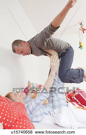 Stock Photo - Smiling couple playing in bed together. Fotosearch