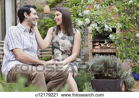 Smiling couple sitting together outdoors View Large Photo Image Stock Image - Smiling couple sitting together outdoors. Fotosearch