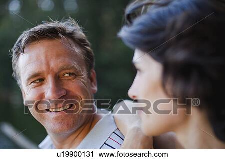 Stock Image - Smiling couple talking outdoors. Fotosearch