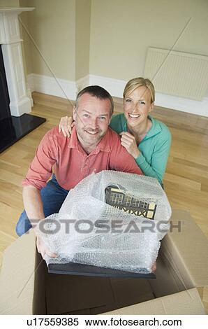 Stock Photography - Smiling couple unpacking in new home. Fotosearch