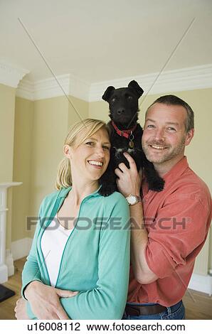 Smiling couple with dog in new home View Large Photo Image Stock Image - Smiling couple with dog in new home. Fotosearch