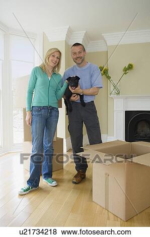 Stock Photo - Smiling couple with dog in new home. Fotosearch