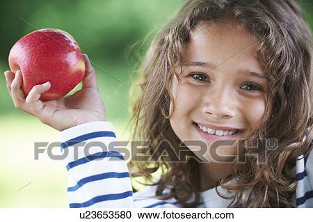 Smiling girl holding an apple View Large Photo Image Stock Image - Smiling girl holding an apple. Fotosearch