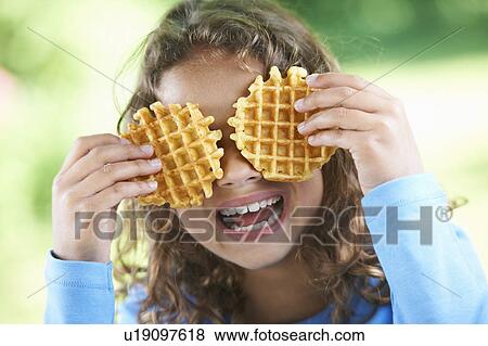 Stock Photo - Smiling girl playing with waffles. Fotosearch