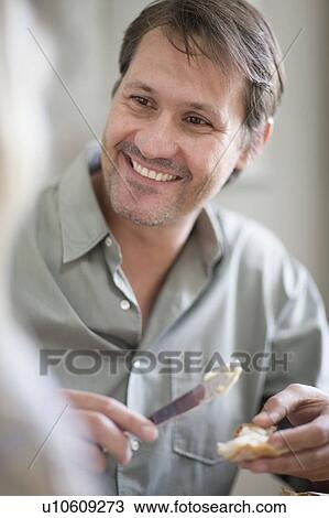 Stock Image - Smiling man buttering bread. Fotosearch