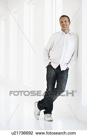 Smiling man leaning against wall View Large Photo Image Stock Image - Smiling man leaning against wall . Fotosearch