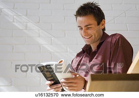Smiling man reading book View Large Photo Image Stock Image - Smiling man reading book . Fotosearch