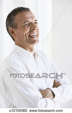 Stock Image - Smiling man standing with arms folded. Fotosearch