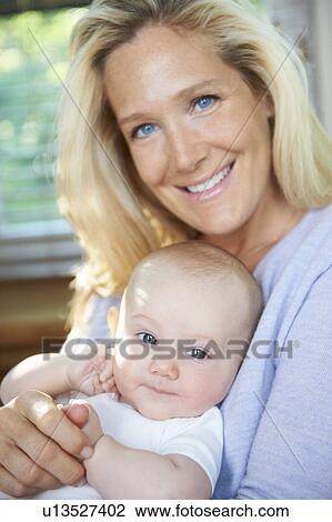 Stock Image - Smiling mother holding baby. Fotosearch