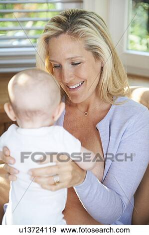 Stock Photo - Smiling mother holding baby. Fotosearch
