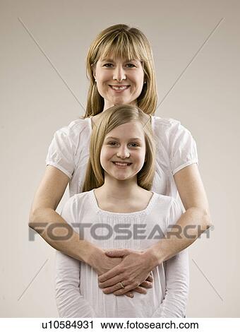 Stock Image - Smiling mother hugging daughter. Fotosearch