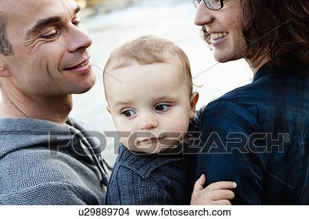 Smiling parents holding baby View Large Photo Image Picture - Smiling parents holding baby. Fotosearch