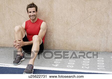 Smiling runner sitting against wall View Large Photo Image Stock Image - Smiling runner sitting against wall. Fotosearch