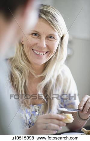 Smiling woman buttering bread View Large Photo Image Stock Photo - Smiling woman buttering bread. Fotosearch