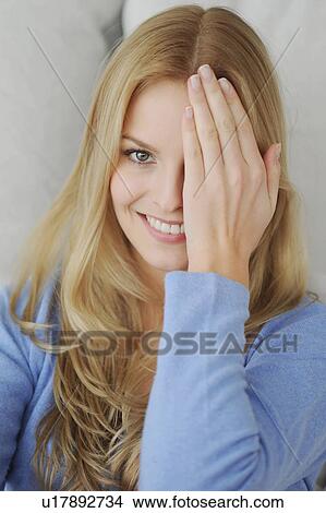 Picture - Smiling woman covering one eye. Fotosearch