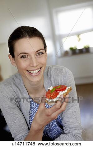 Stock Photo - Smiling woman eating tomato sandwich. Fotosearch