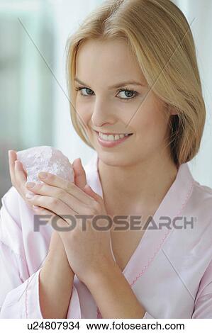 Picture - Smiling woman holding rose quartz. Fotosearch