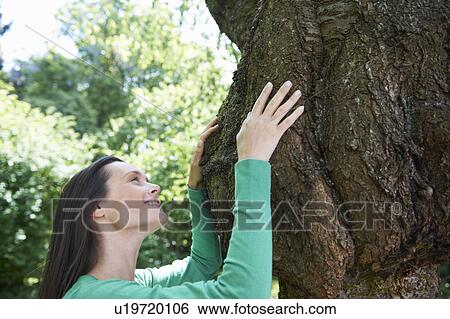 Stock Photograph - Smiling woman hugging tree. Fotosearch