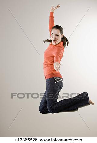 Stock Photograph - Smiling woman jumping in mid air. Fotosearch