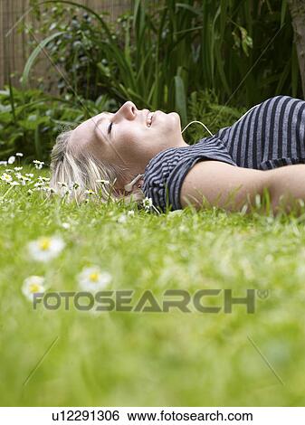 Smiling woman laying in grass View Large Photo Image Stock Photograph - Smiling woman laying in grass. Fotosearch