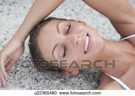 Smiling woman laying on stone View Large Photo Image Stock Image - Smiling woman laying on stone. Fotosearch
