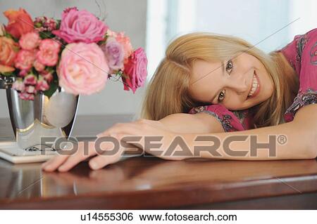 Stock Photograph - Smiling woman laying on table. Fotosearch