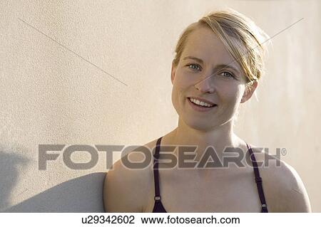 Smiling woman leaning against wall View Large Photo Image Stock Image - Smiling woman leaning against wall . Fotosearch