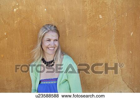 Smiling woman leaning against wall View Large Photo Image Stock Photo - Smiling woman leaning against wall. Fotosearch