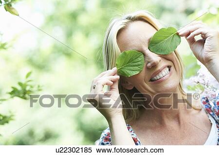 Stock Photography - Smiling woman playing with leaves. Fotosearch